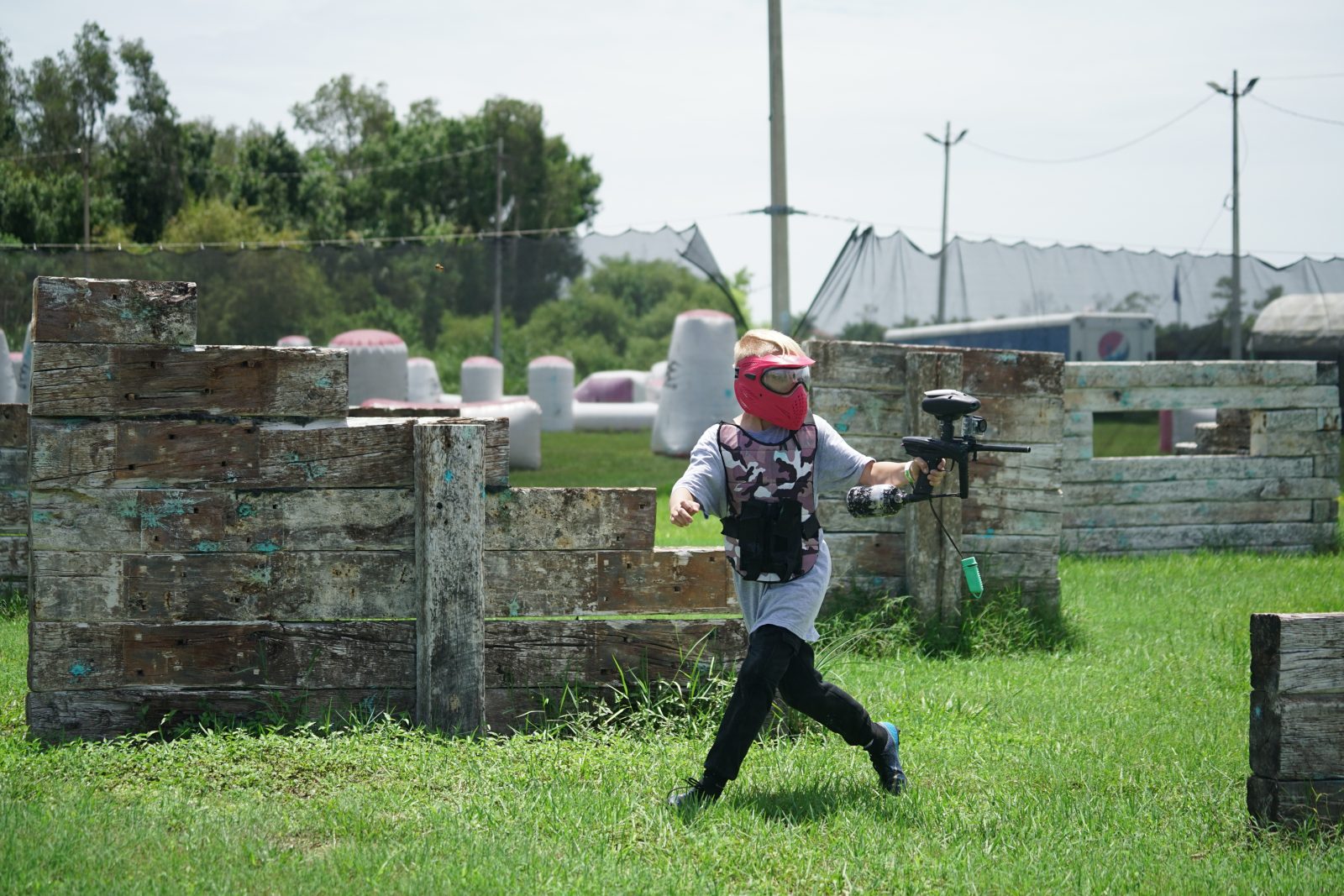 Paintball player running between wooden bunkers at Fort Myers Paintball Park
